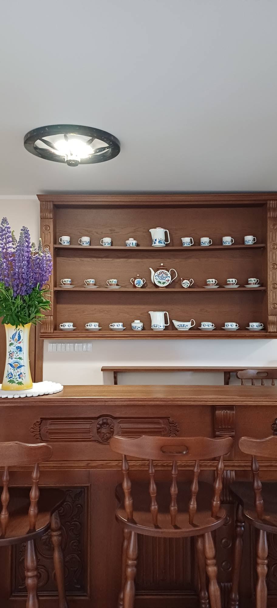 Drewniany kredens z kolekcją kaszubskiej porcelany i wazonem z łubinem
